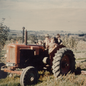 old picture of Bill Montague riding a tractor with his kids